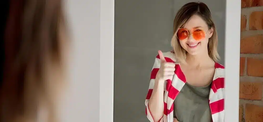 joven feliz vistiendose cerca espejo gafas sol min