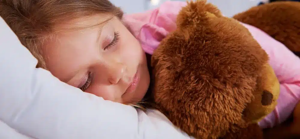 nina durmiendo con osito de peluche su dormitorio min